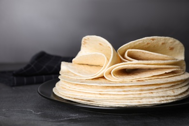 Plate with stack of tasty tortillas on grey table, closeup. Space for text