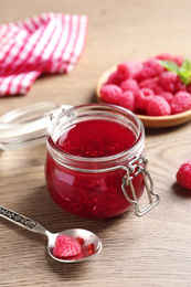 Sweet raspberry jam and fresh berries on wooden table