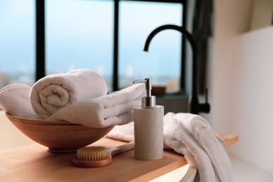 Photo of Clean towels, soap dispenser and shower brush in bathroom