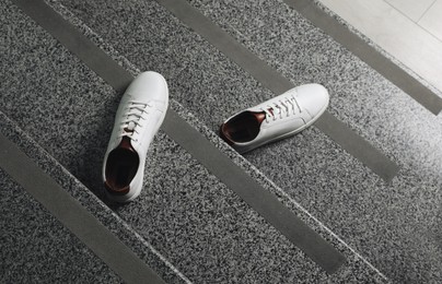 Photo of Pair of stylish sports shoes on stairs, top view