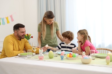 Photo of Happy family celebrating Easter at served table in room