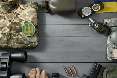 Photo of MYKOLAIV, UKRAINE - SEPTEMBER 26, 2020: Frame of tactical gear and Ukrainian military uniform on grey table, flat lay. Space for text
