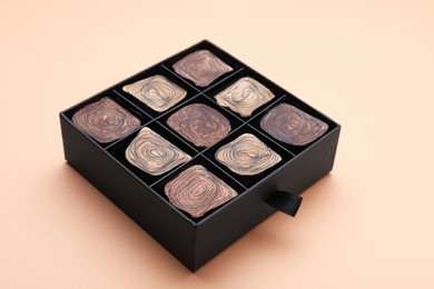 Photo of Box of tasty chocolate candies on beige background, closeup
