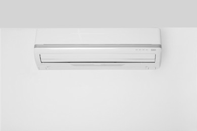 Photo of Modern air conditioner on white wall indoors. Space for text