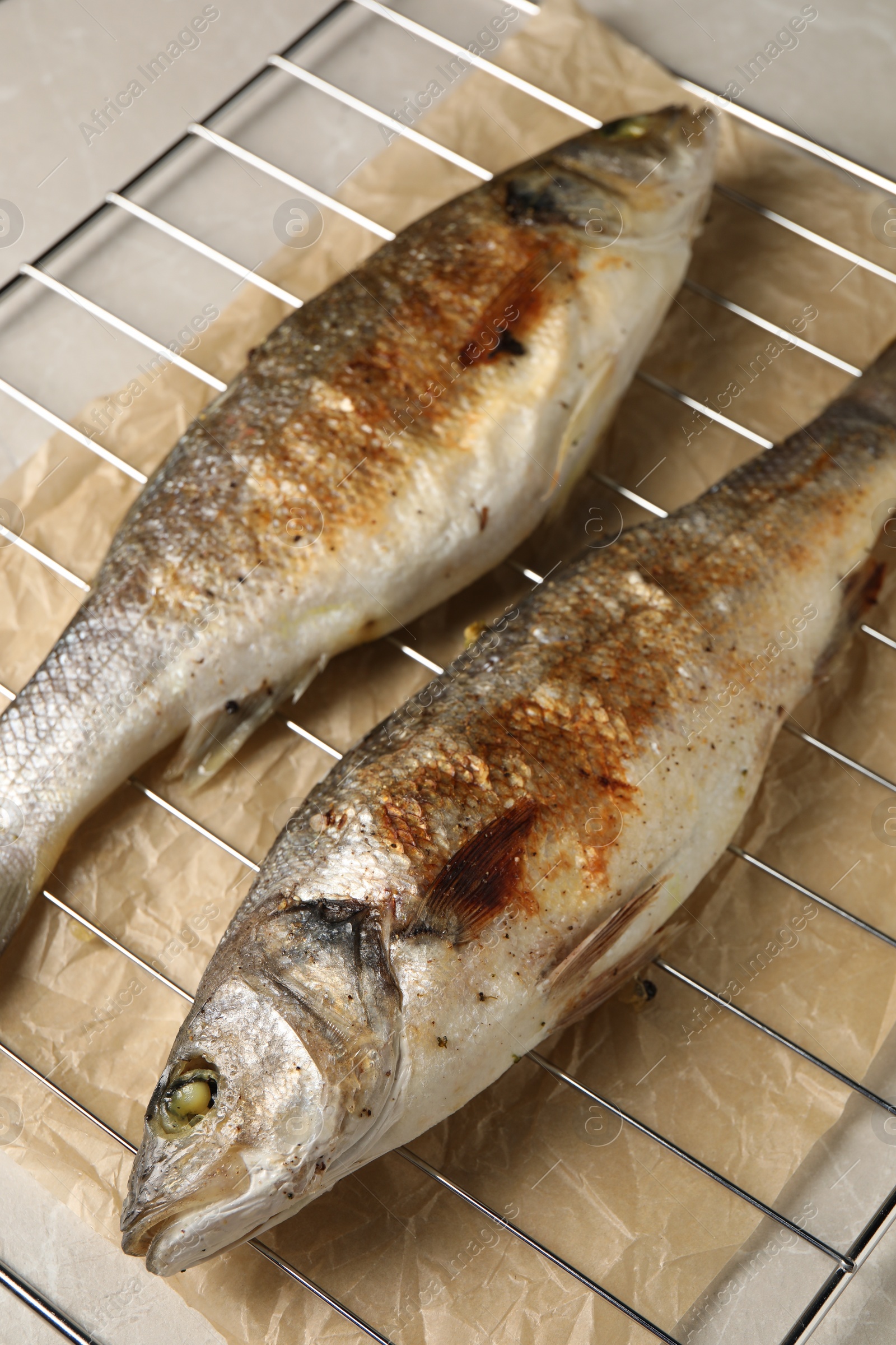 Photo of Baked fish on light marble table, closeup