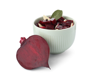 Photo of Pickled beets with garlic in bowl and half of vegetable on white background