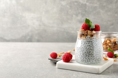 Delicious chia pudding with raspberries and granola on grey table. Space for text