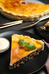 Photo of Piece of delicious pie with minced meat, basil and sauce served on table, closeup