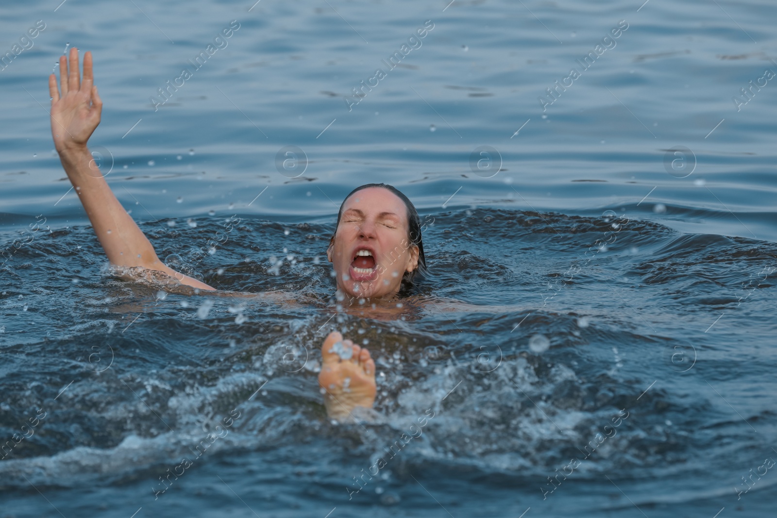 Photo of Drowning woman reaching for help in sea