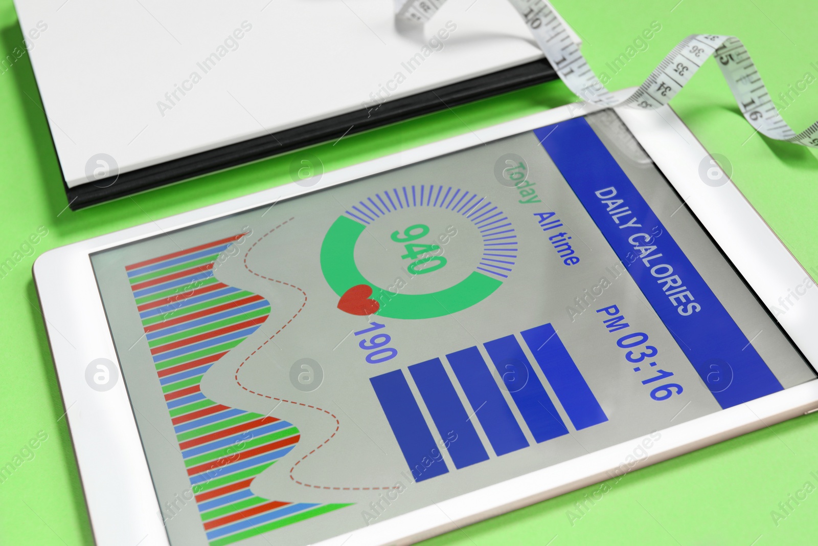 Photo of Tablet with weight loss calculator application and measuring tape on green background, closeup