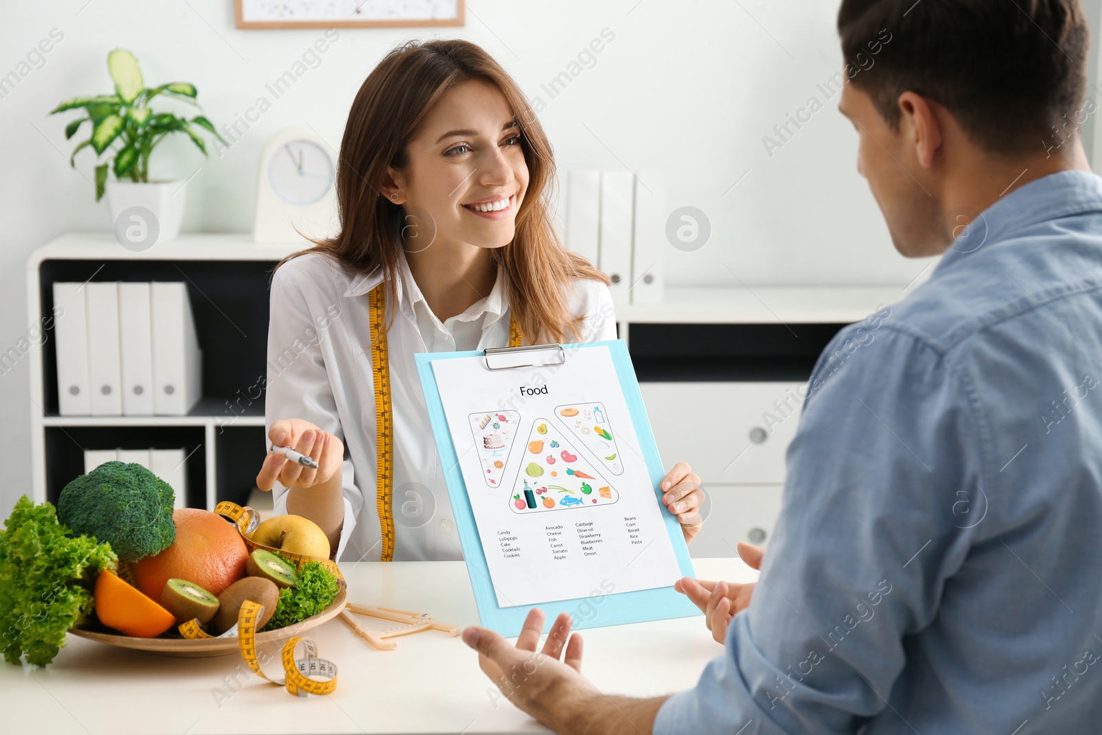 Photo of Young nutritionist consulting patient at table in clinic
