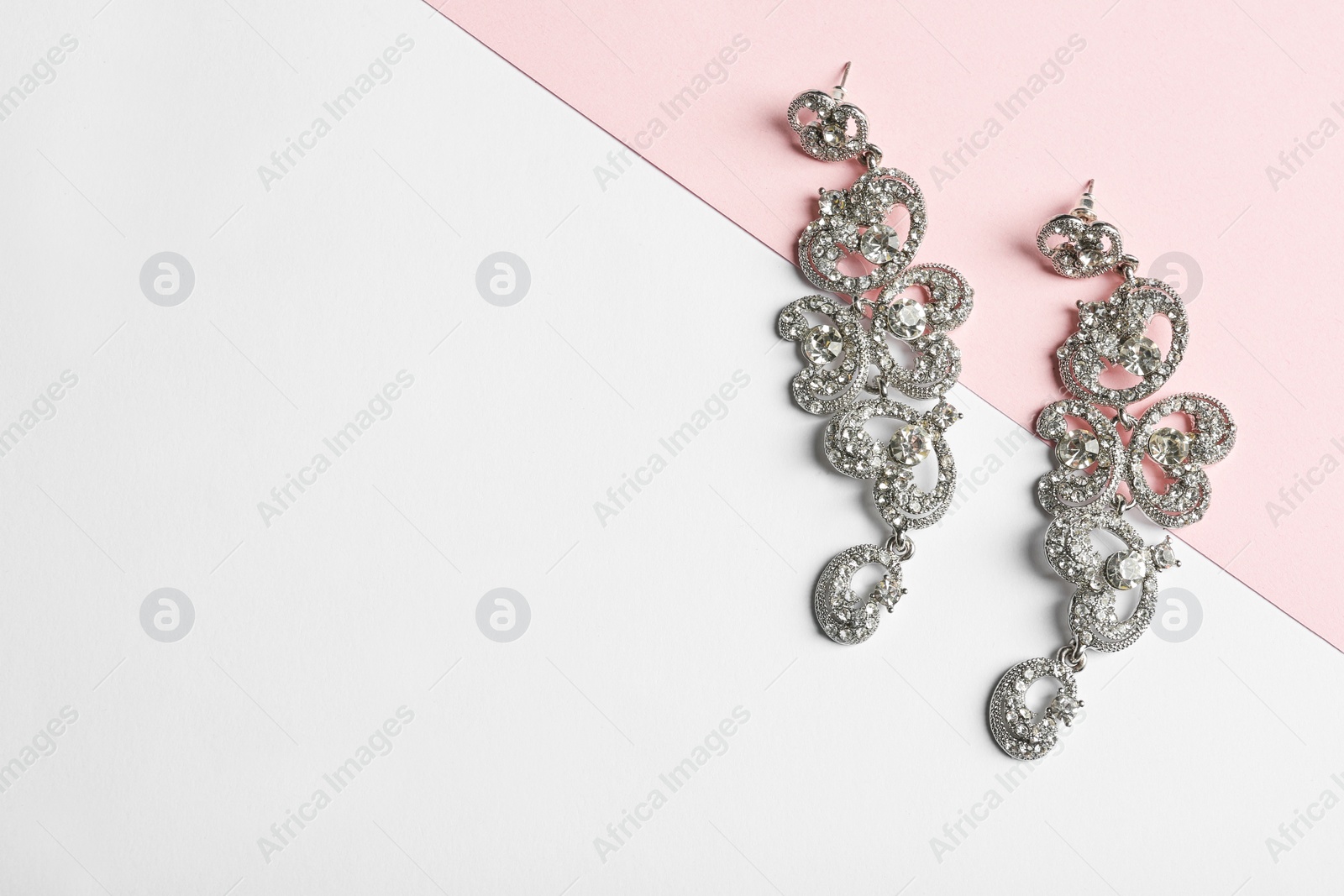Photo of Elegant earrings on color background, top view with space for text. Luxury jewelry