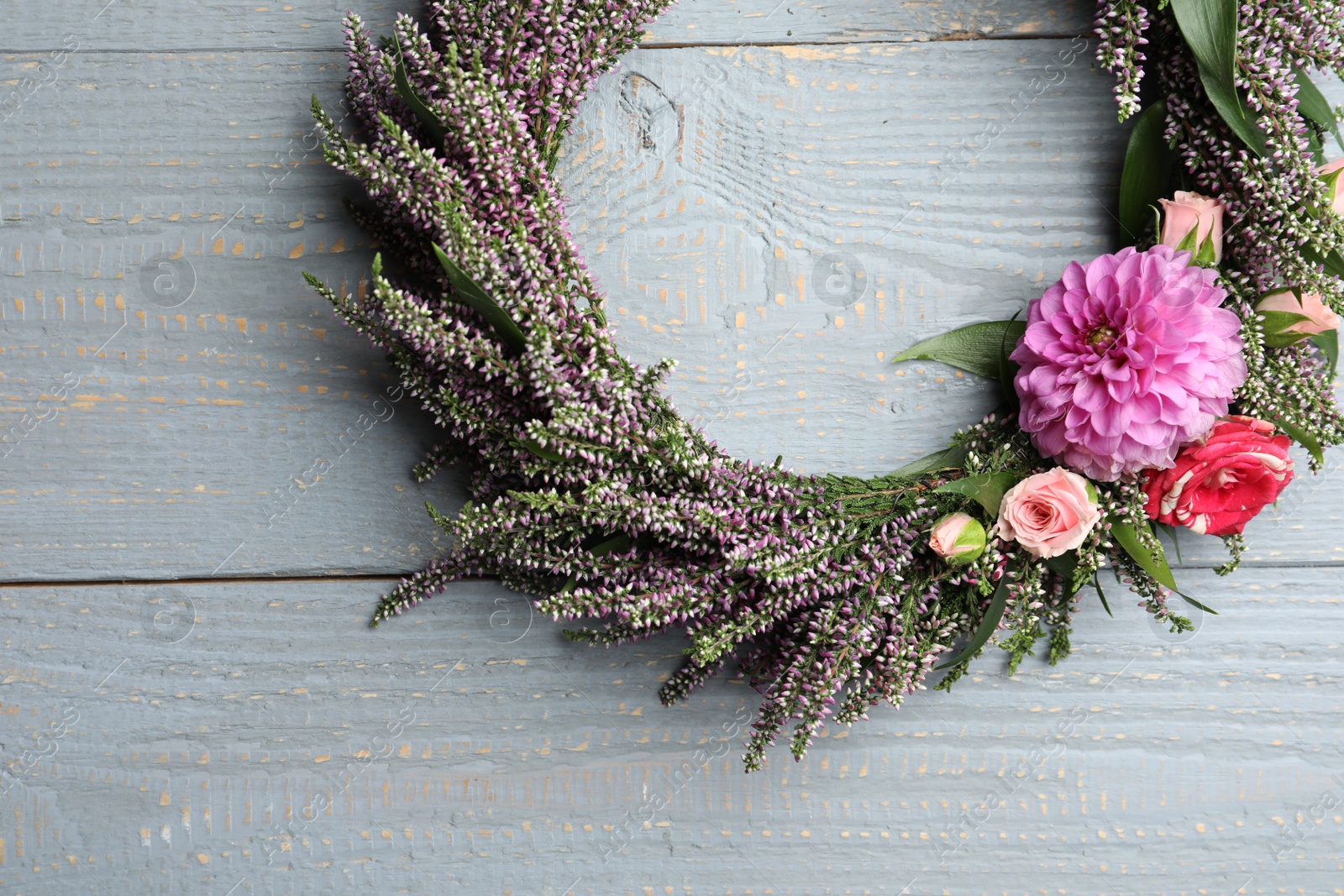 Photo of Beautiful autumnal wreath with heather flowers on light grey wooden background, top view. Space for text