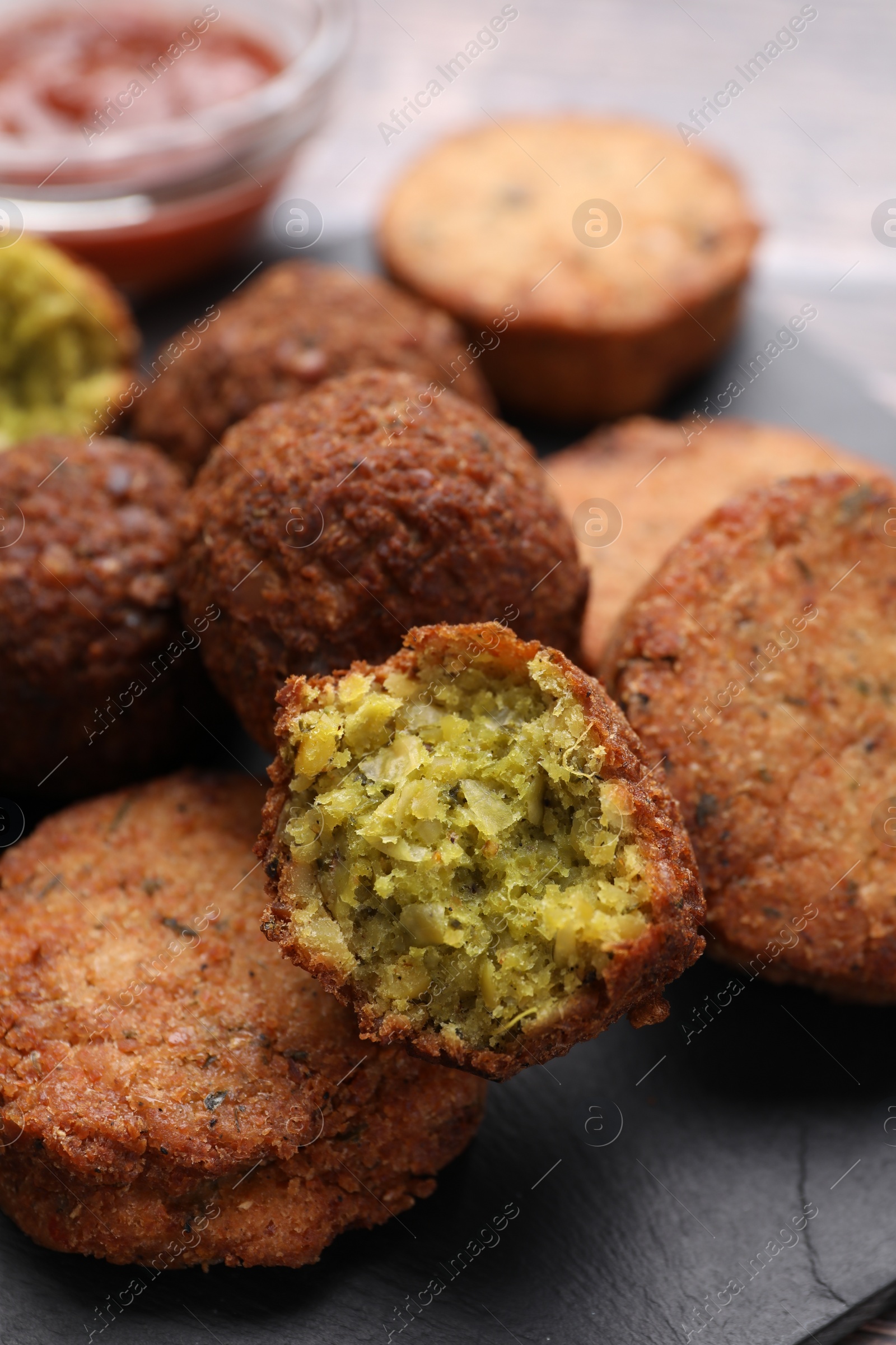 Photo of Delicious vegan cutlets and falafel balls on slate board, closeup