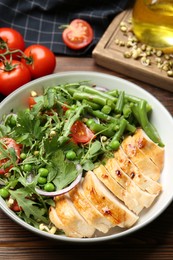 Photo of Healthy meal. Tasty salad and chicken breast in bowl on wooden table