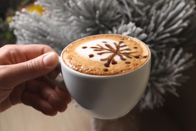 Photo of Woman holding cup of aromatic coffee near fir branch, closeup