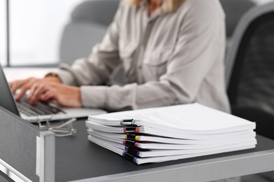 Photo of Businesswoman working with laptop at grey table in office, focus on documents. Space for text