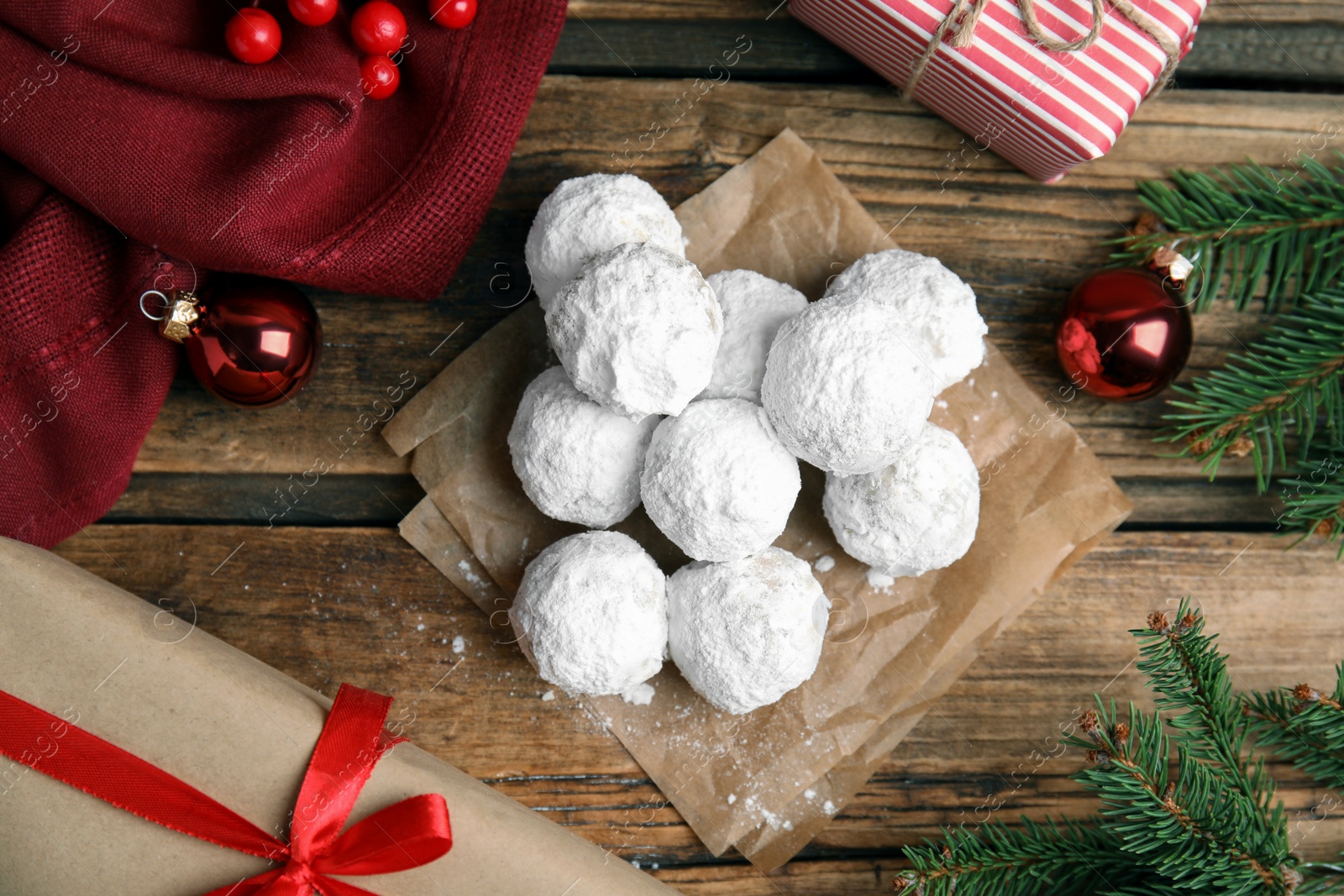 Photo of Tasty snowball cookies and Christmas decorations on wooden table, flat lay