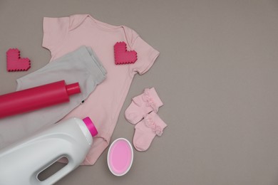 Photo of Bottles of laundry detergents, baby clothes and decorative hearts on grey background, flat lay. Space for text