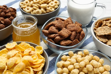 Photo of Different delicious breakfast cereals, milk and honey on kitchen towel