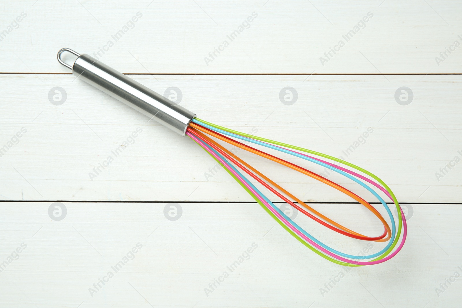 Photo of One whisk on white wooden table, top view