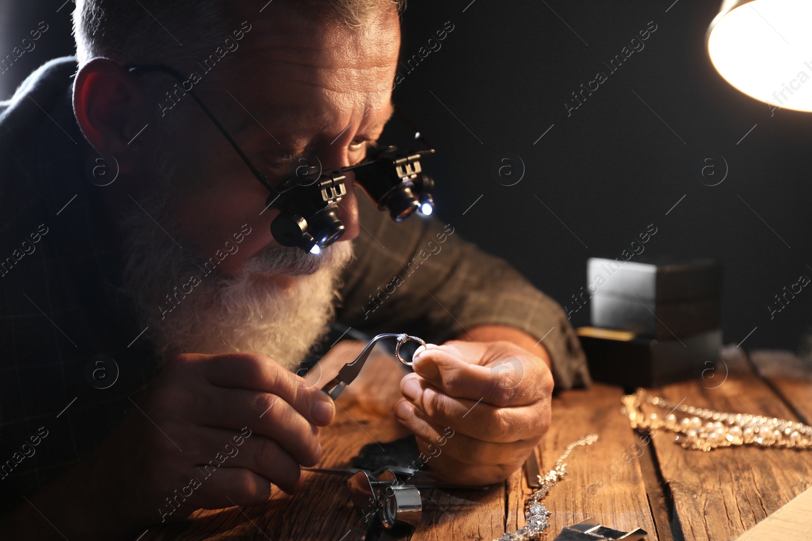 Photo of Male jeweler evaluating diamond ring in workshop