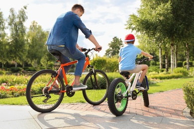 Photo of Dad and son riding modern bicycles outdoors