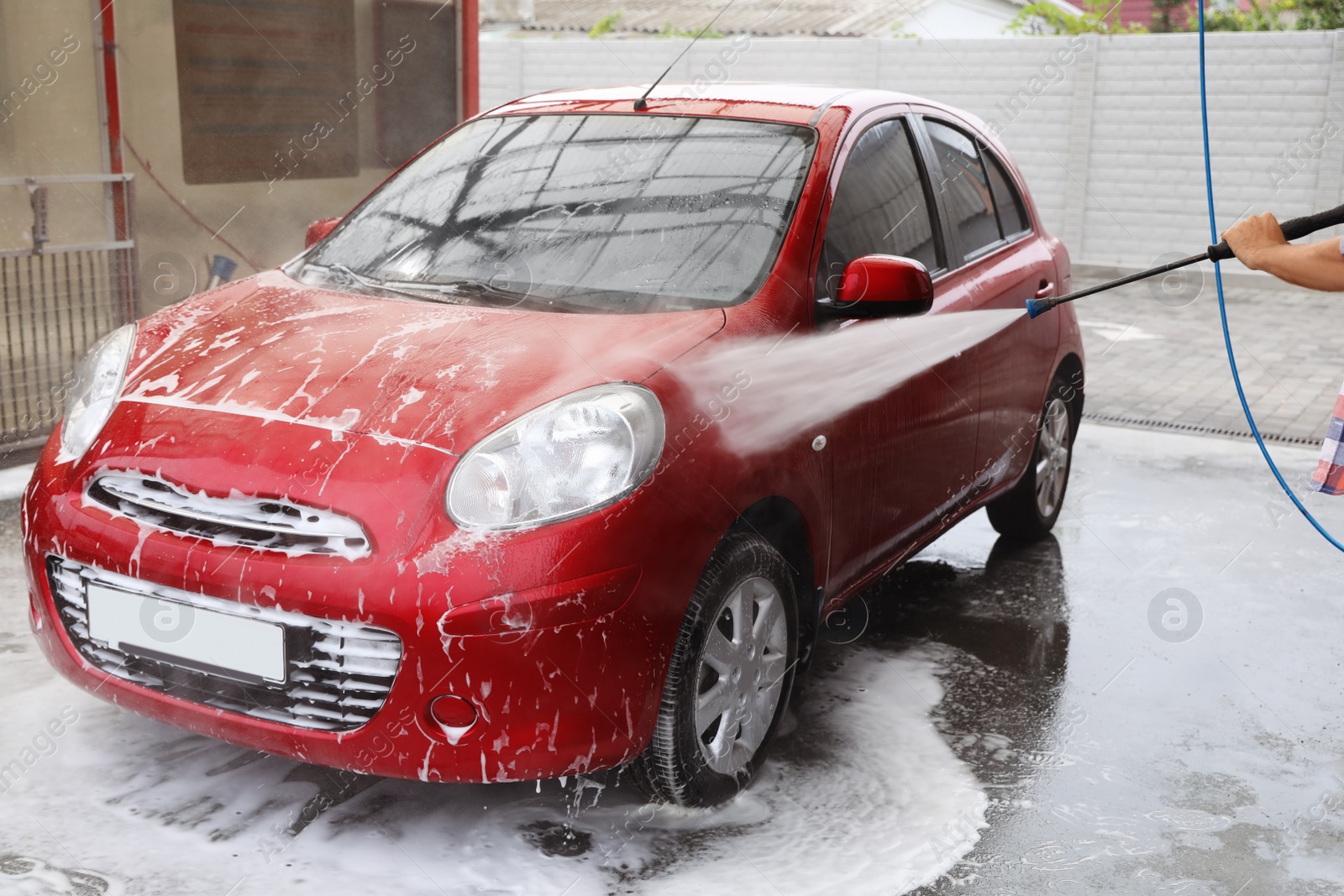 Photo of Man cleaning auto with high pressure water jet at car wash