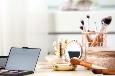 Photo of Different makeup products and accessories on dressing table in room interior