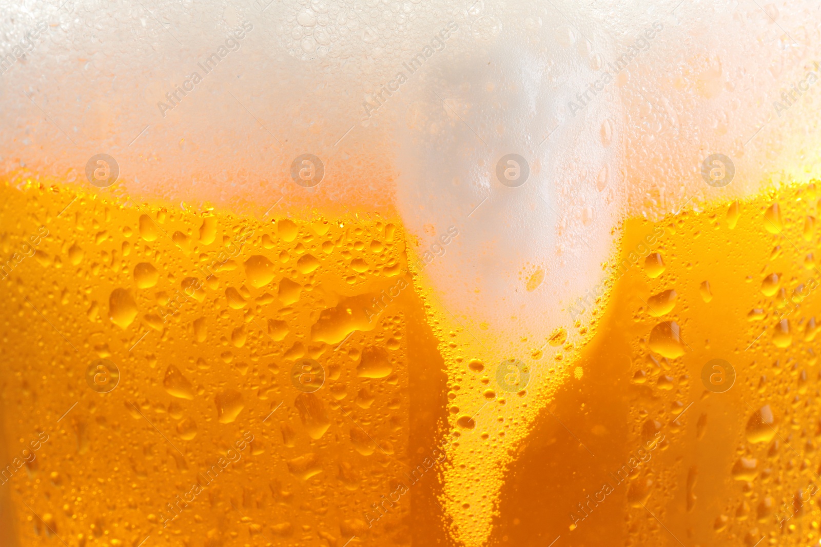 Photo of Glass of tasty cold beer with foam and condensation drops as background, closeup