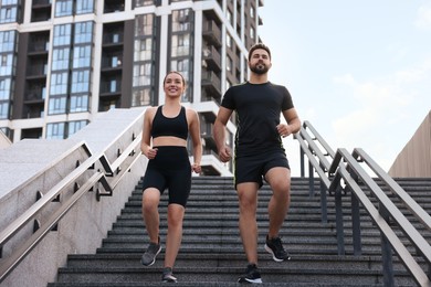 Healthy lifestyle. Happy couple running on steps outdoors, low angle view