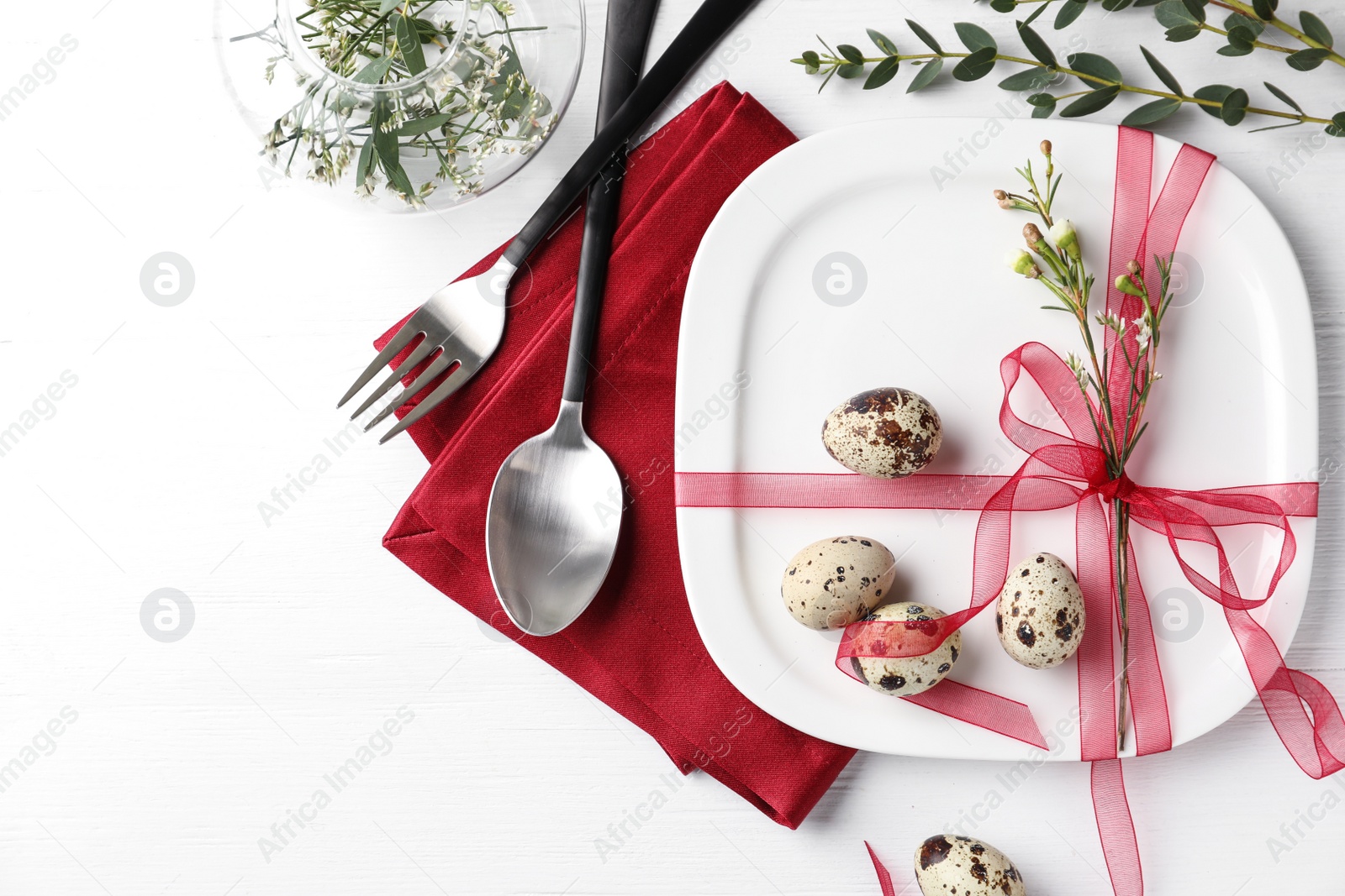 Photo of Festive Easter table setting with ribbon and quail eggs on white wooden background, flat lay