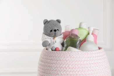 Photo of Basket full of different baby cosmetic products and toy on blurred background, closeup