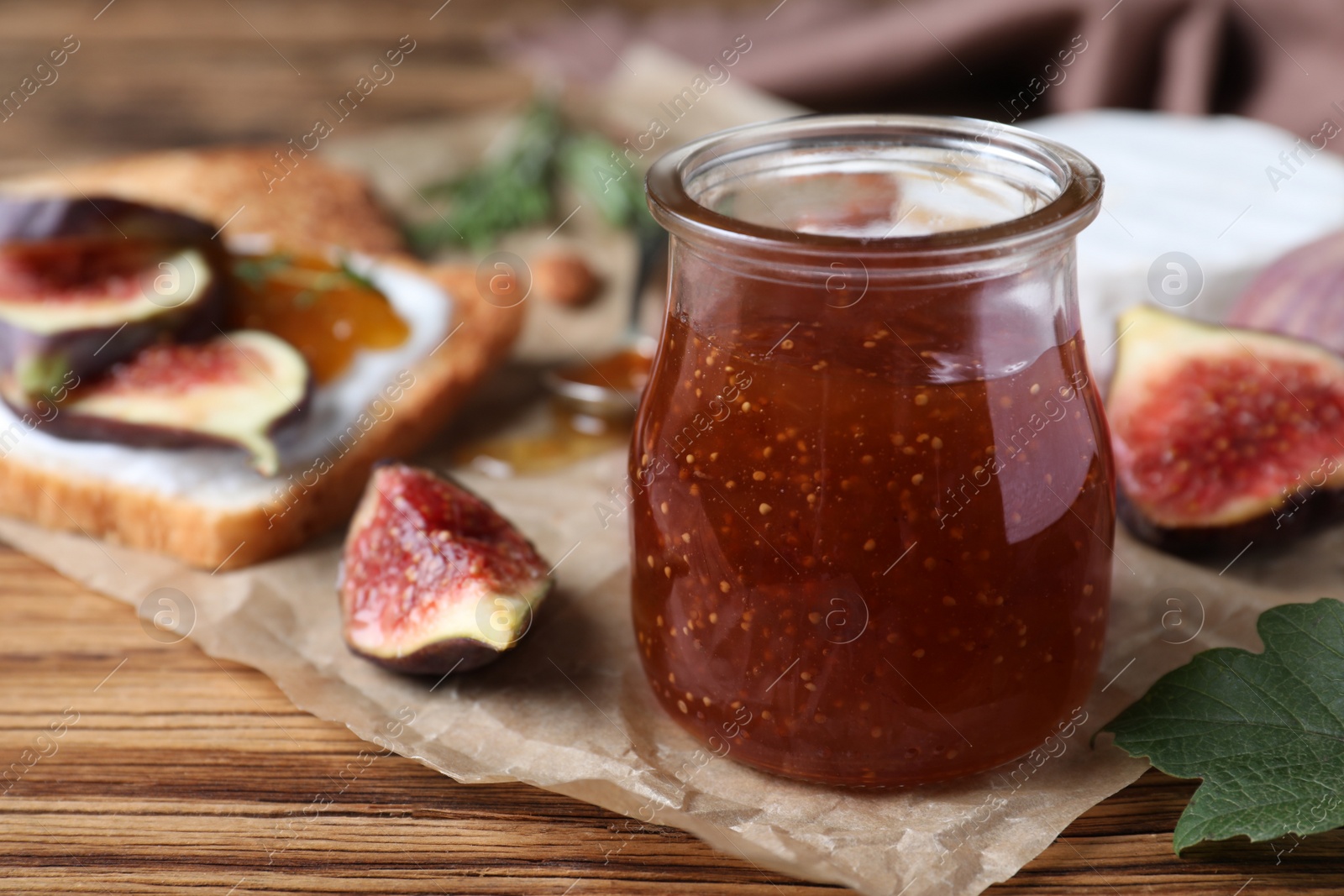 Photo of Delicious fig jam on wooden table, closeup. Space for text