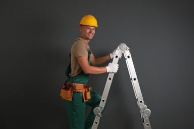 Photo of Professional constructor climbing ladder on black background