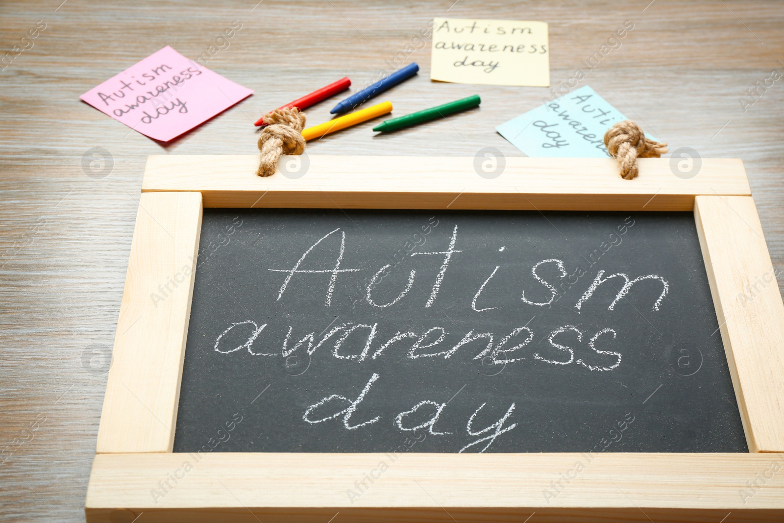 Photo of Chalkboard with phrase "Autism awareness day" on wooden background