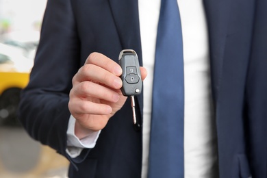 Photo of Businessman with key in dealership. Buying new car