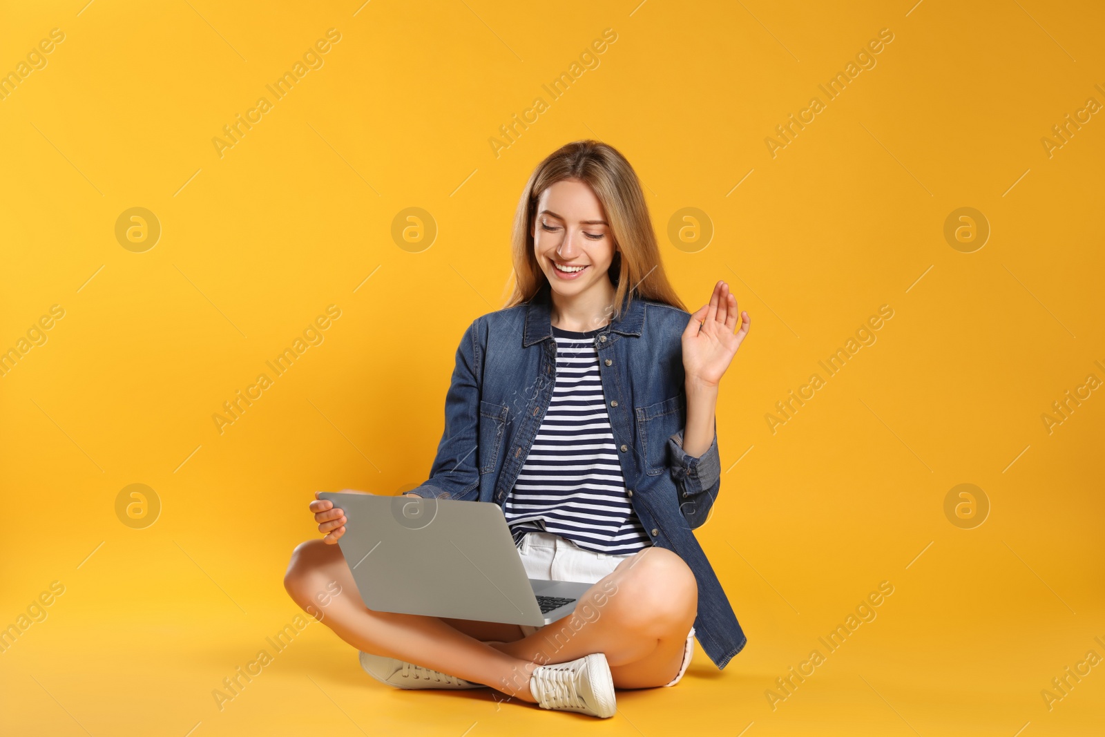 Photo of Young woman with laptop on yellow background