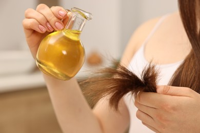 Woman applying oil hair mask at home, closeup