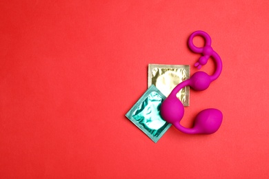 Photo of Anal balls and condoms on red background, top view with space for text. Sex game