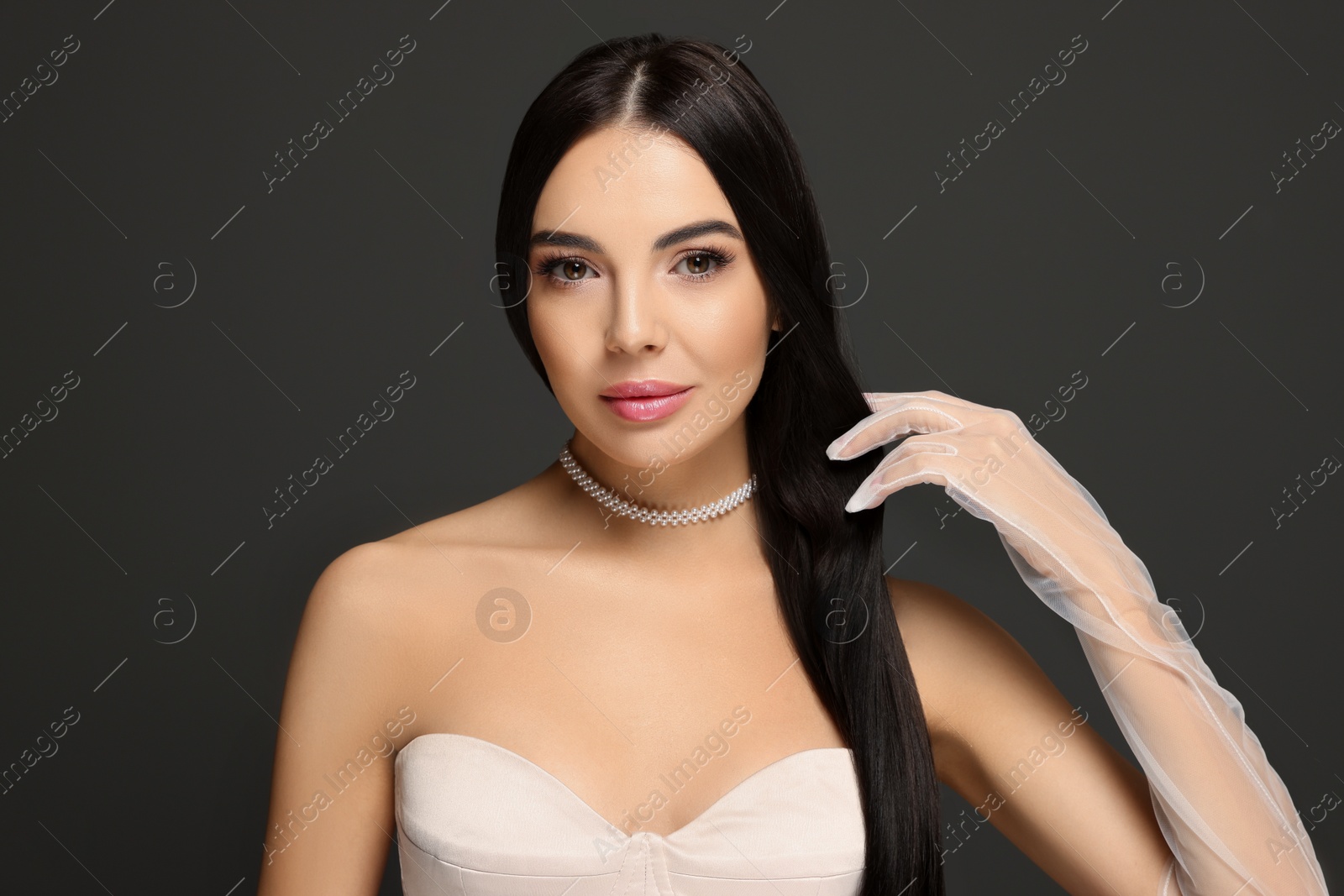 Photo of Portrait of beautiful young woman in evening gloves on black background