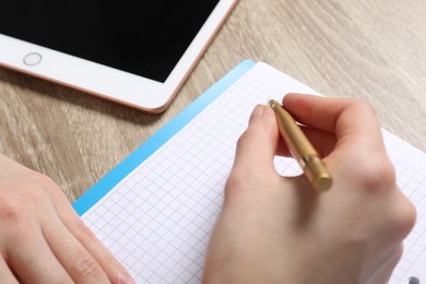 Photo of Woman taking notes at wooden table, closeup