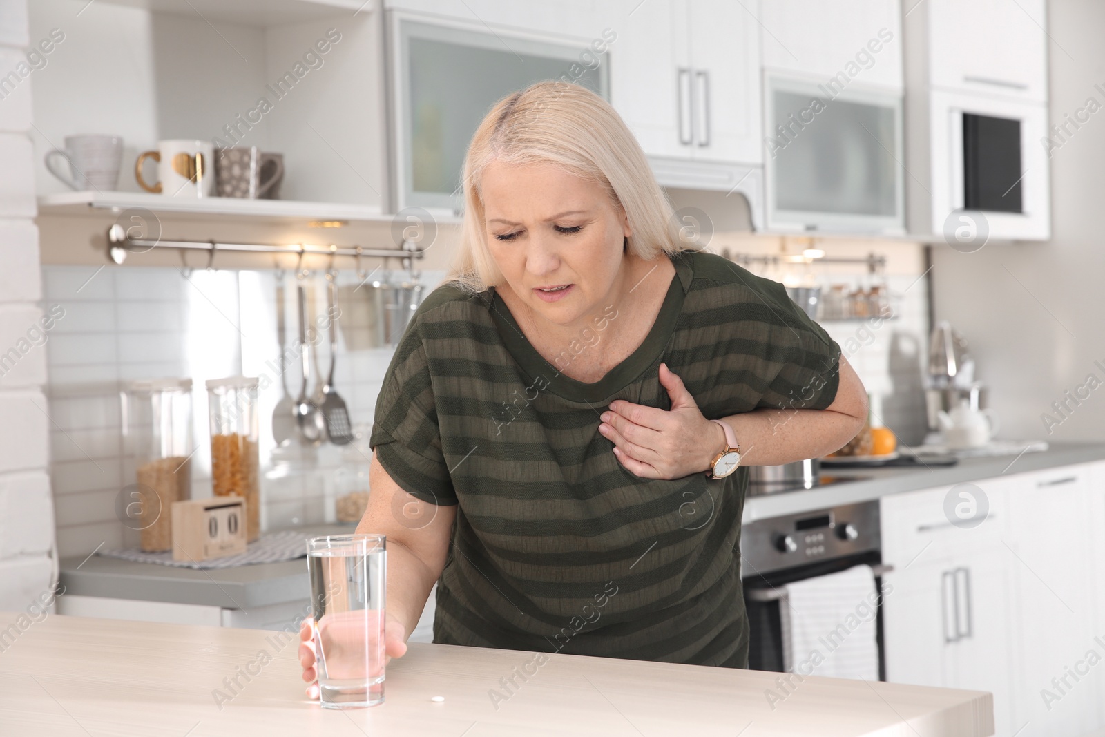 Photo of Mature woman having heart attack in kitchen