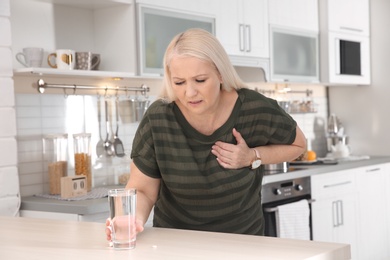 Mature woman having heart attack in kitchen