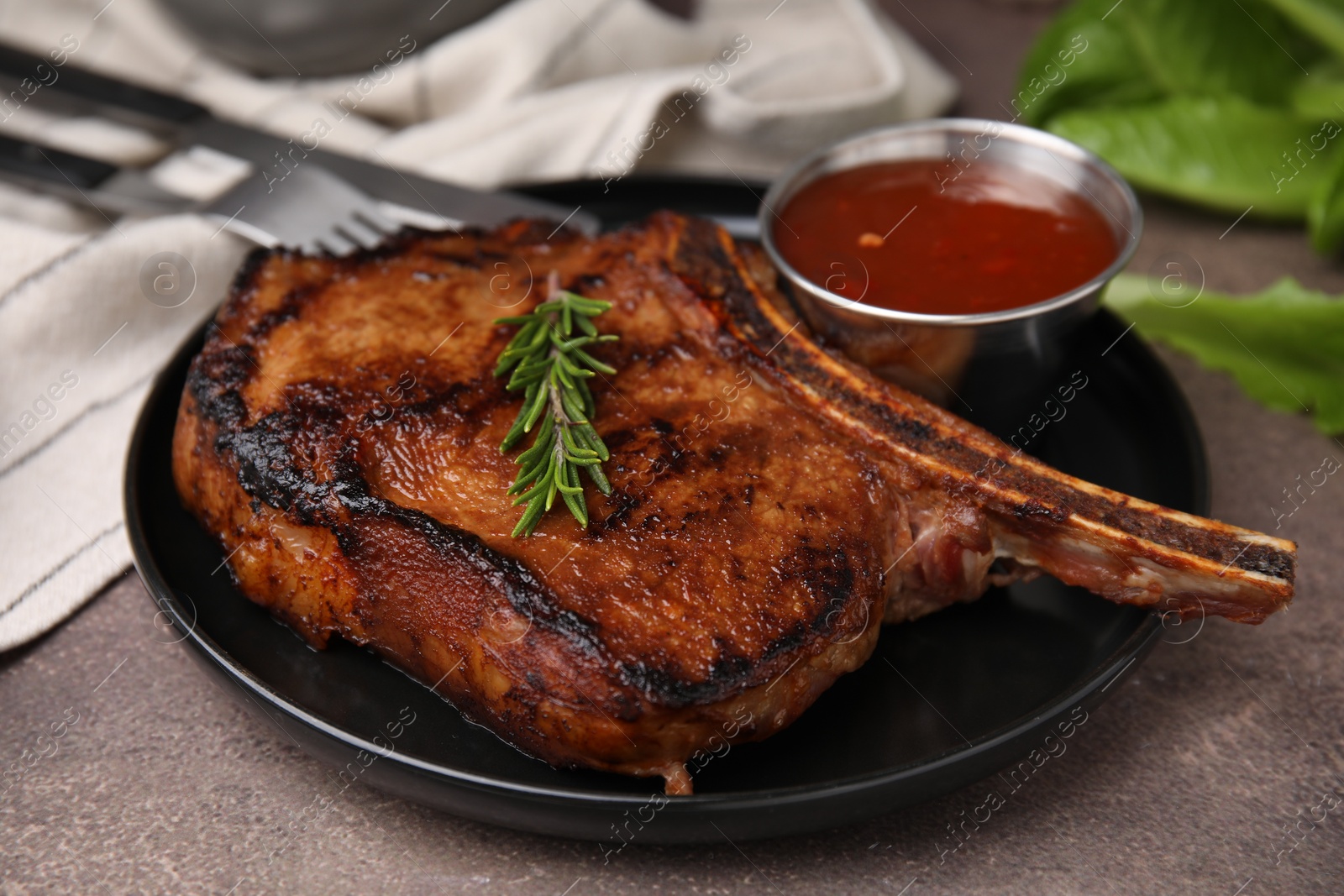 Photo of Tasty grilled meat, rosemary and marinade on brown textured table, closeup