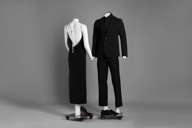 Male and female mannequins dressed in elegant outfits on grey background