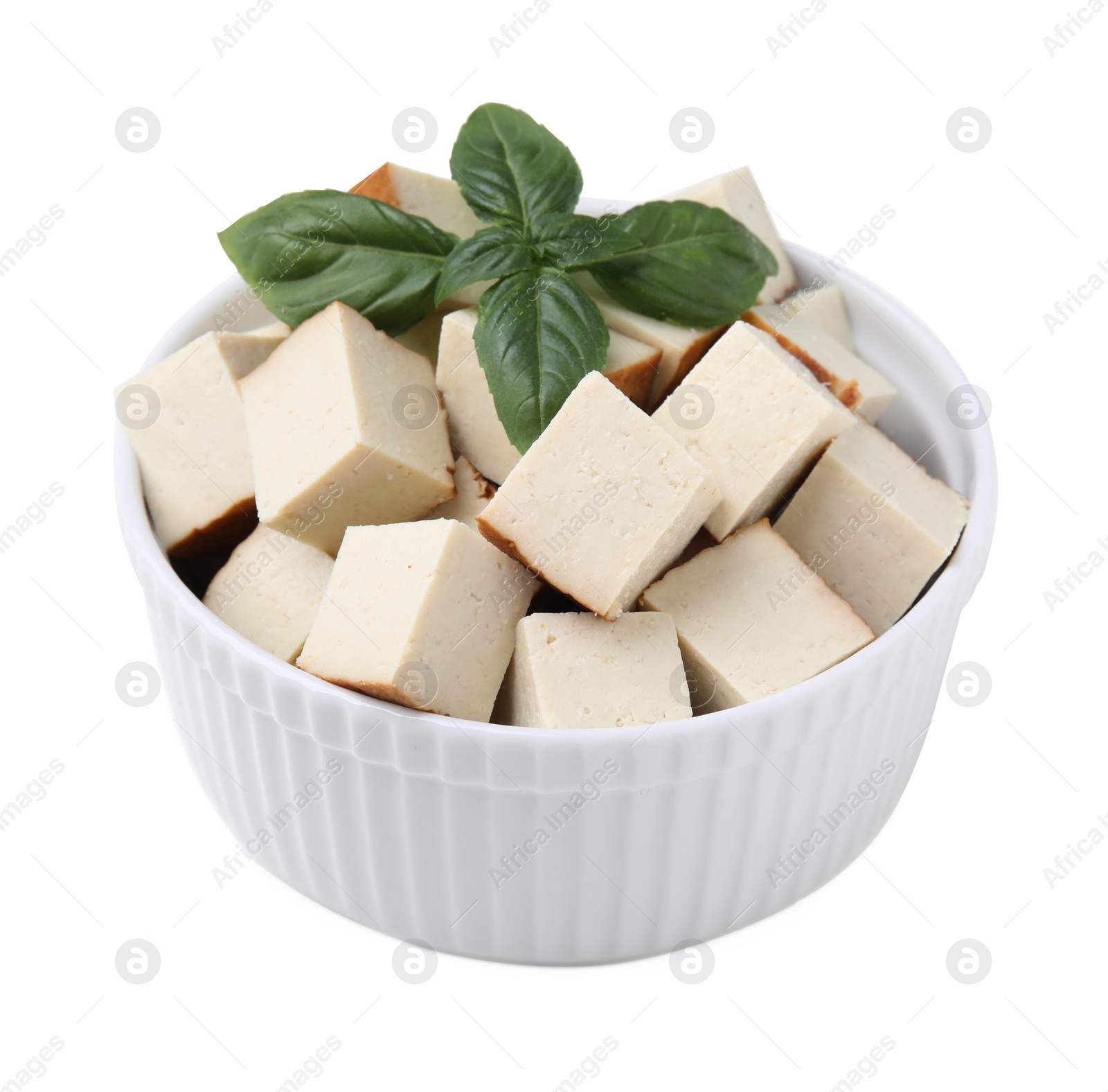 Photo of Bowl of delicious smoked tofu cubes with basil isolated on white