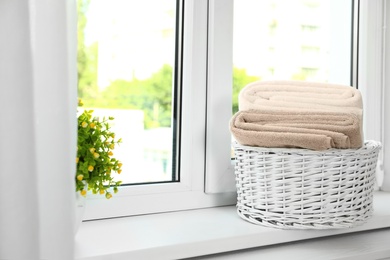 Basket with clean soft towels on window sill. Space for text