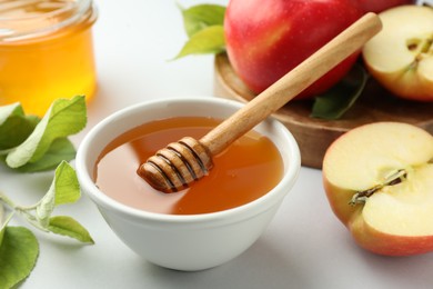 Photo of Sweet honey and fresh apples on white table, closeup