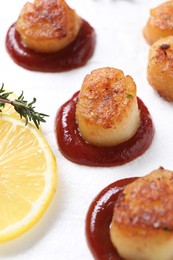 Photo of Delicious fried scallops with tomato sauce and lemon on plate, closeup